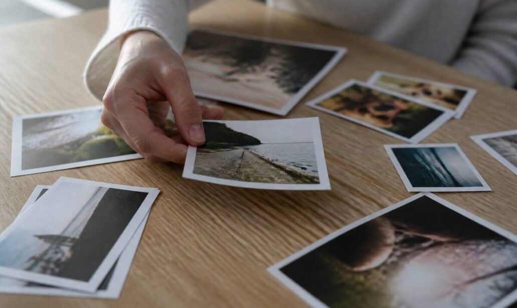 Hand die fotoafdrukken kiest op een houten tafel bij daglicht