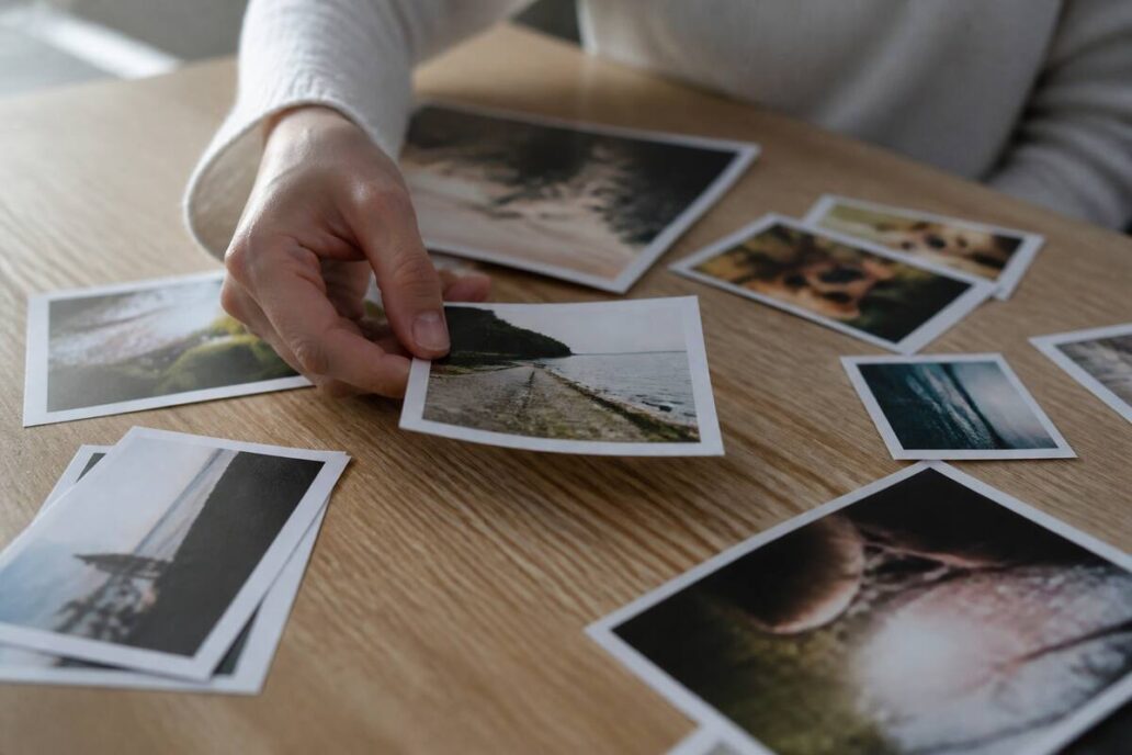 Hand die fotoafdrukken kiest op een houten tafel bij daglicht