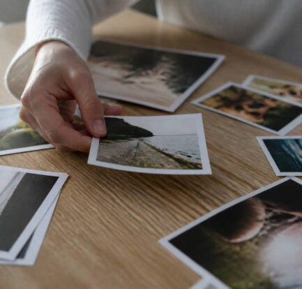 Hand die fotoafdrukken kiest op een houten tafel bij daglicht
