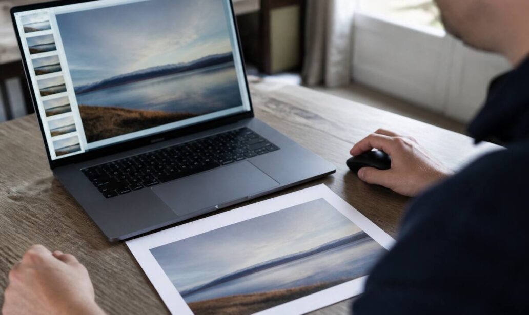 Close-up van het controleren van foto’s op een laptop en een printproef op tafel