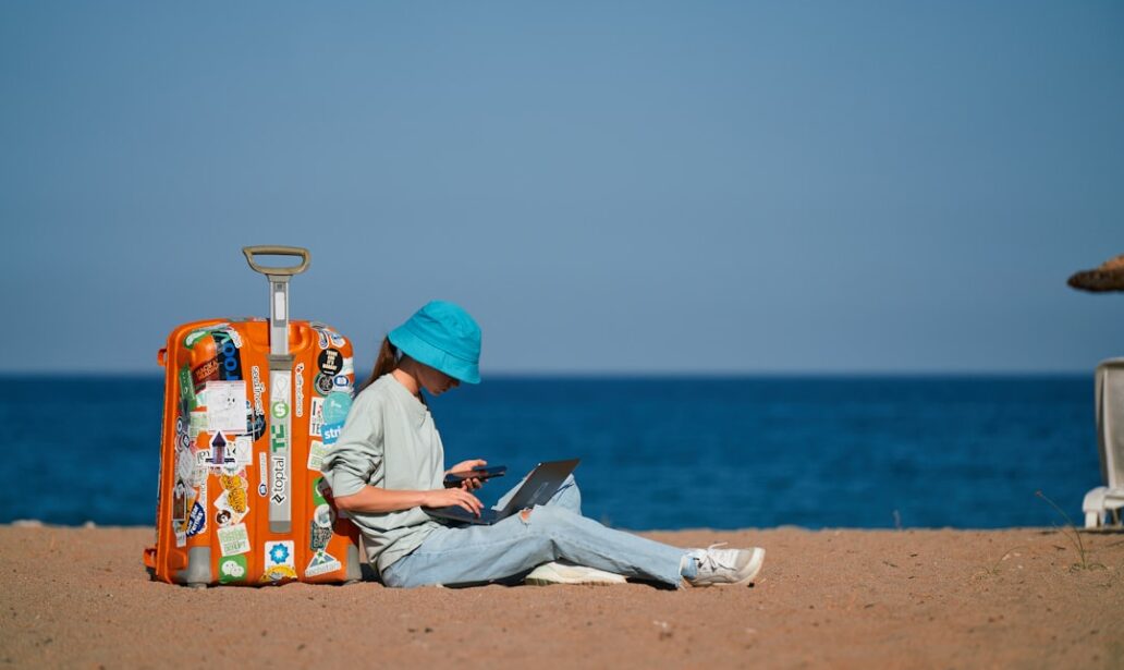 a person sitting on the beach with a suitcase