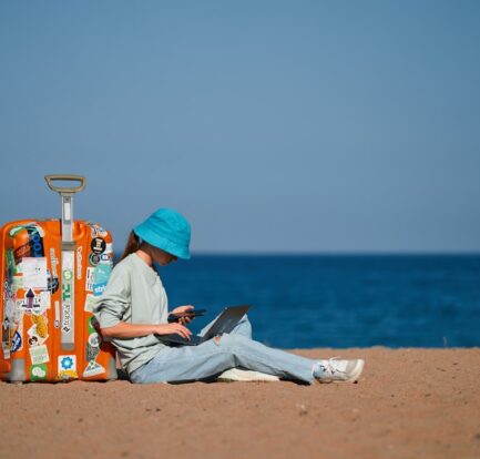 a person sitting on the beach with a suitcase