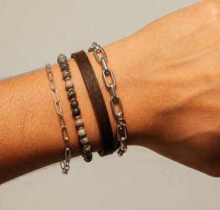 Close-up van armbanden op een pols met verschillende materialen bij warm daglicht